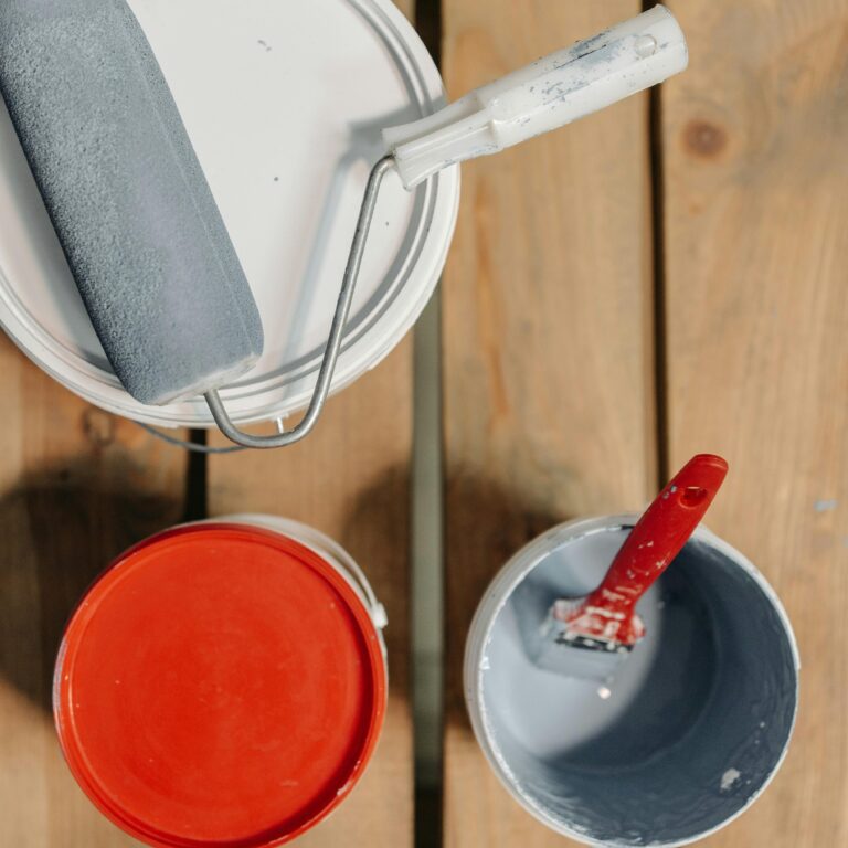 Paint cans and brushes arranged on wooden boards, ready for renovation work.